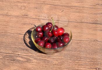 Berries of a sweet cherry in a glass bowl on a wooden background. Ripe red sweet cherry.
