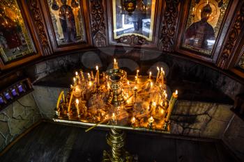 Burning candles on a stand near the icons in the chapel. Attributes of Orthodox Christianity.