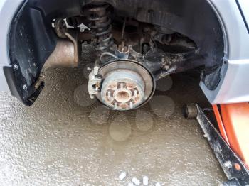 The car is at the tire shop. Under the jack the car in car-care center. The car with the removed wheel