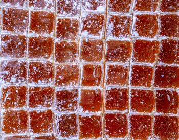Cubes of marmalade, powdered with powdered sugar. Background from cubes of marmalade.