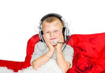 The boy in musical earphones with a microphone was screwed by hands for a face. The boy lies on the bed and listens to music with headphones.