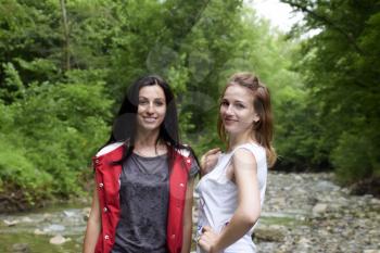 Nibirjay, Russia - June 24, 2017: Girls blonde and brunette against the background of a mountain river and forest. Posing against the backdrop of the mountainous terrain.