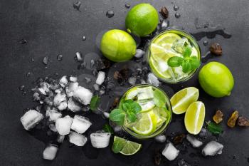 Summer mint lime refreshing cocktail mojito with rum and ice in glass on black background top view