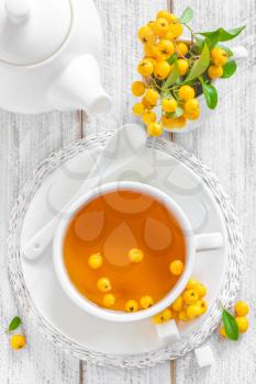 Fresh warmer herbal hawthorn tea with fresh berries in a white cup on wooden background, alternative medicine