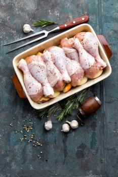 Raw uncooked chicken legs, drumsticks on wooden board, meat with ingredients for cooking, top view