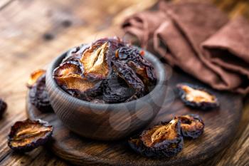 Prune, dried plums fruits on dark rustic wooden background