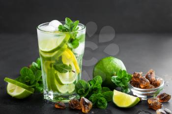 Refreshing mint cocktail mojito with rum and lime, cold drink or beverage with ice on black background