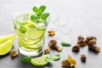 Summer mint lime refreshing cocktail mojito with rum and ice in glass on black background