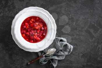 Vegetarian hot diet beetroot soup with vegetables on plate, top view, dark background