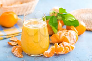 Tangerines, peeled tangerines and tangerine juice in glass. Mandarine juice and fresh fruits with leaves.