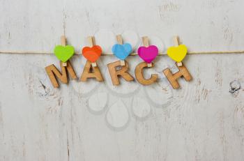 word March and multicolored hearts on a white background old wooden