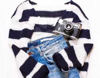 Women's clothing, sweater, jeans and a camera on a white background. The concept of fashionable, stylish women. Top view, flat