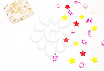 Gift with decor from stars, confetti on a white background. The composition of the present in  gold wrapping paper and stars , Christmas decorations. Christmas, New Year's ,birthday background