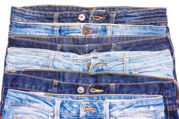 Many different blue jeans in a row on a white background