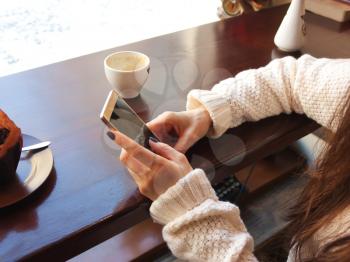 hand girl, woman, holding phone in hand, sitting in a cafe