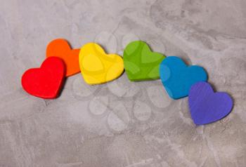 wooden hearts of the color of the rainbow on a cement background. The LGBT symbol