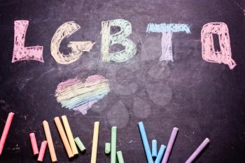  word LGBTQ is written with crayons of the color of the rainbow on the board