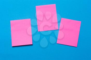 Three empty pink notes, a sticker on a blue background for writing ideas and tasks