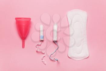 coral Pad, menstrual cup, tampon on a pink background. The view is flat. Concept of critical days, menstruation