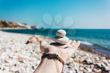 Balance of stones on the hand against the background of the sea. The concept of peace of mind, harmony, spirituality