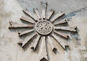 The sign of the sun is abstract on a gray concrete, cement wall.An ancient symbol