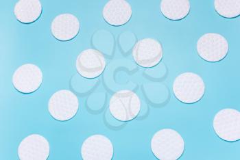 White cotton disks on blue background. Concept of cleanliness, makeup, body care. Top view, flat