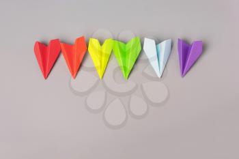 Paper airplanes of rainbow color, LGBT flag on a gray background