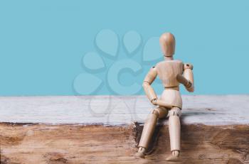 Wooden man mannequin sits on blue background. Place for text .Concept of idea, creative, training