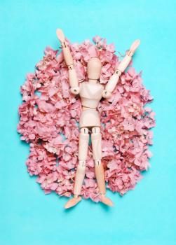 Wooden mannequin on a background of flowers. The concept of art, creativity, joy, happiness