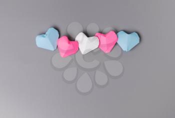 Origami paper hearts in transgender flag colors on gray background