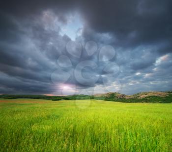 Green meadow in mountain and heavy rainy cloud. Composition of nature.