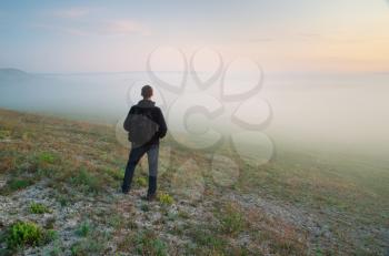 Man standing in fog meadow. 