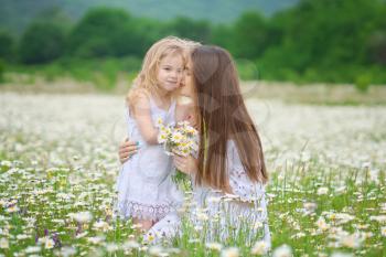 Happy mother and daughter in big camomile mountain meadow. Emotional, love and care scene.