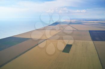 Patchwork meadows and fields and sea. Farmlands from above. Aerial view of agricultural meadows. Nature composition.