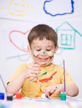 Portrait of a cute boy showing her hands painted in bright colors