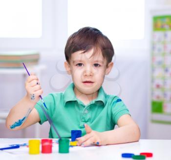 Portrait of a cute little boy playing with paints