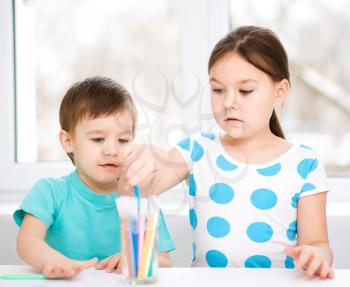 Little children is drawing on white paper using color pencils