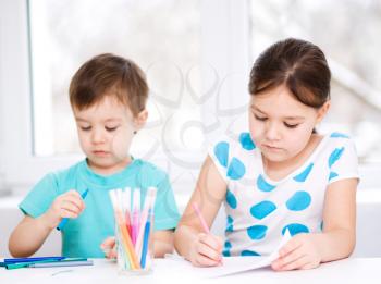 Little children is drawing on white paper using color pencils