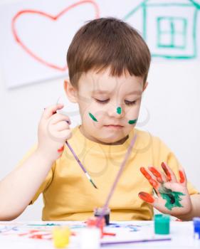 Portrait of a cute boy showing her hands painted in bright colors