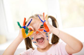 Portrait of a cute cheerful girl showing her hands painted in bright colors