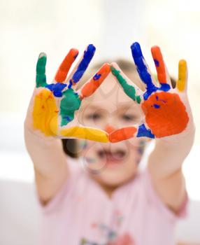 Portrait of a cute cheerful girl showing her hands painted in bright colors