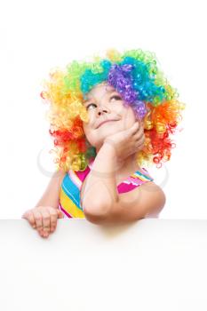 Cute girl in clown wig is holding blank banner, isolated over white