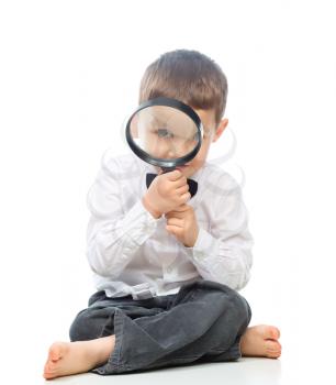 Cute little boy is looking through magnifier, isolated over white