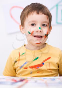 Portrait of a cute little boy playing with paints
