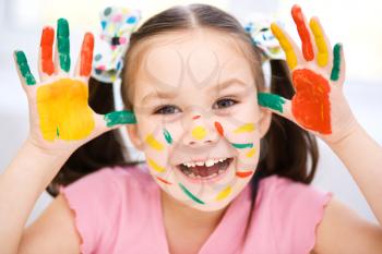 Portrait of a cute cheerful girl showing her hands painted in bright colors