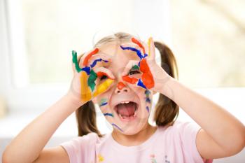 Portrait of a cute cheerful girl showing her hands painted in bright colors