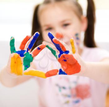 Portrait of a cute cheerful girl showing her hands painted in bright colors