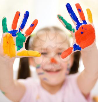 Portrait of a cute cheerful girl showing her hands painted in bright colors