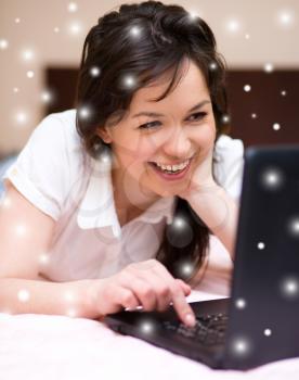 Young woman is playing on laptop, over snowy background