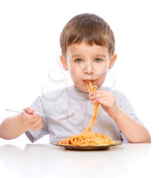 Little boy is eating spaghetti using fork, isolated over white